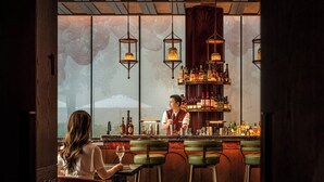 Zona de bar con techo de madera, faroles colgantes y un barman detrás de la barra.