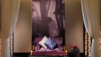 Una habitación con cama, un área de descanso adosada a la pared y un adorno mural.