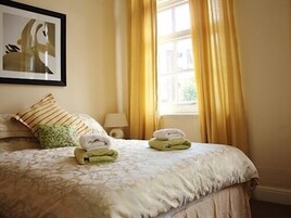 Una cama bien hecha con una colcha estampada, una almohada y dos toallas dobladas sobre la cama.