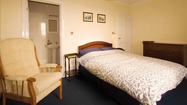A bedroom with a bed, a chair, a bedside table, and a dresser. - East House (Chathill)