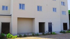 A multi-story residential building with a flat facade, multiple windows, and a central entrance with a blue door. - Meridian Apartments - Southend (Southend-on-Sea)