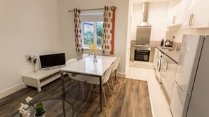 A modern kitchen with white cabinets, a built-in oven, and a stainless steel refrigerator. - Meridian Apartments - Southend (Southend-on-Sea)