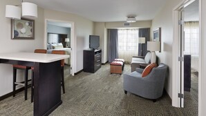 A hotel room with a bed, a desk with a chair, a sofa, a TV, and a lamp. - Staybridge Suites Philadelphia- Montgomeryville by IHG (North Wales)