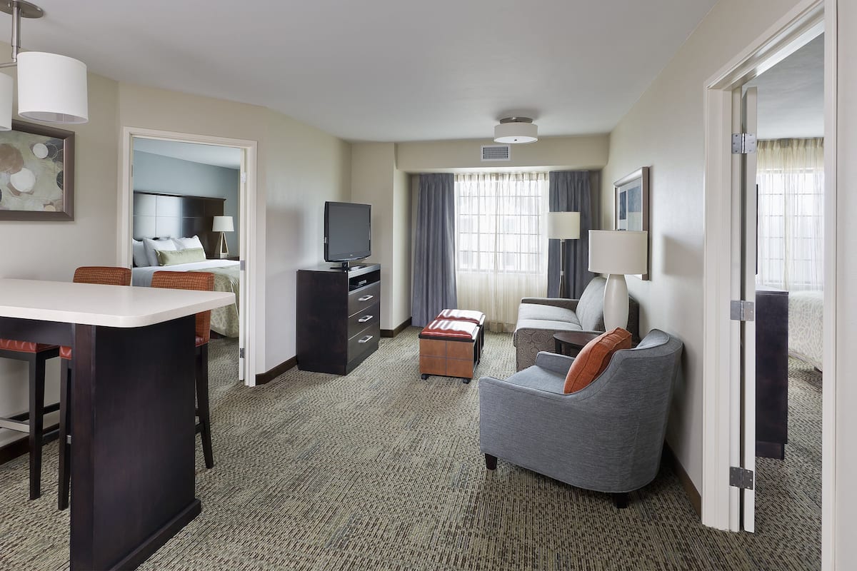 Una habitación de hotel con una cama, un escritorio con una silla, un sofá, un televisor y una lámpara.