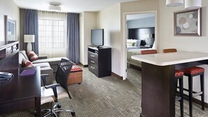 A hotel room with a desk, a chair, a bed, a TV, and a dining area. - Staybridge Suites Philadelphia- Montgomeryville by IHG (North Wales)
