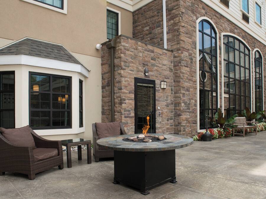 A patio area with a fire pit, seating, and a stone wall.