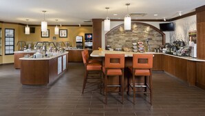A modern kitchen with a stone backsplash, wooden bar counter, and bar stools. - Staybridge Suites Philadelphia- Montgomeryville by IHG (North Wales)