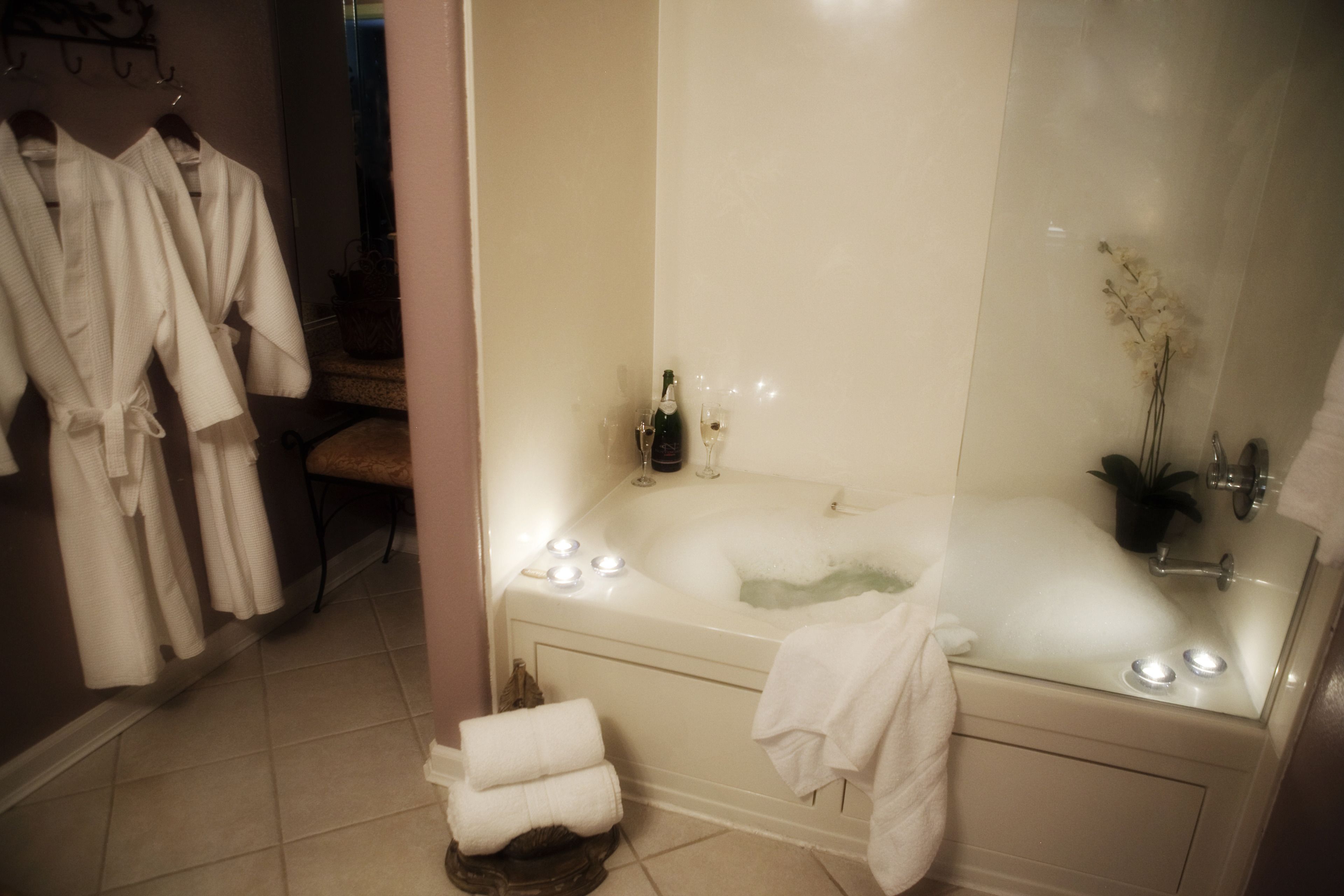 A bathroom with a bathtub, a mirror, and a towel rack with robes.