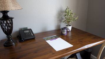 A wooden desk with a telephone, a lamp, a plant, and a mug.
