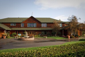 A two-story log cabin with a central courtyard, a stone fountain, and a well-maintained lawn. - The Purple Orchid Wine Country Resort & Spa (Livermore)
