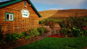 A wooden cabin with a sign reading "The Spa" and a garden with red flowers. - The Purple Orchid Wine Country Resort & Spa (Livermore)