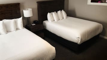 Une chambre d’hôtel avec deux lits simples, une table de chevet avec une lampe et un tableau encadré au mur.