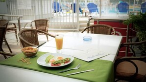 A dining table with a plate of food, a glass of orange juice, and a menu. - Marianna Hotel (Kos)