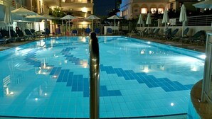 A swimming pool with tiled flooring and lounge chairs around the perimeter. - Marianna Hotel (Kos)