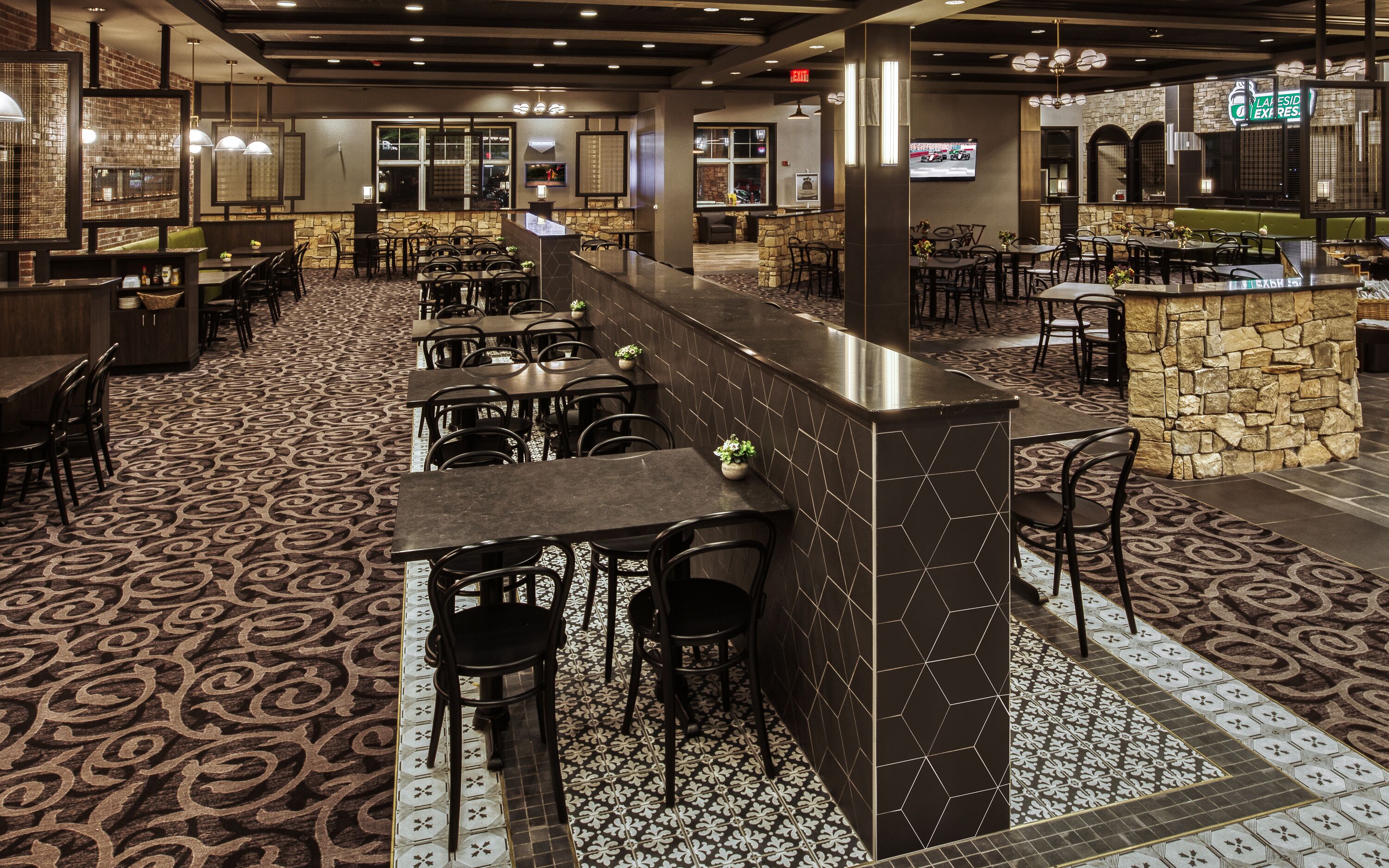A restaurant with a bar area, multiple seating arrangements, and a patterned floor.