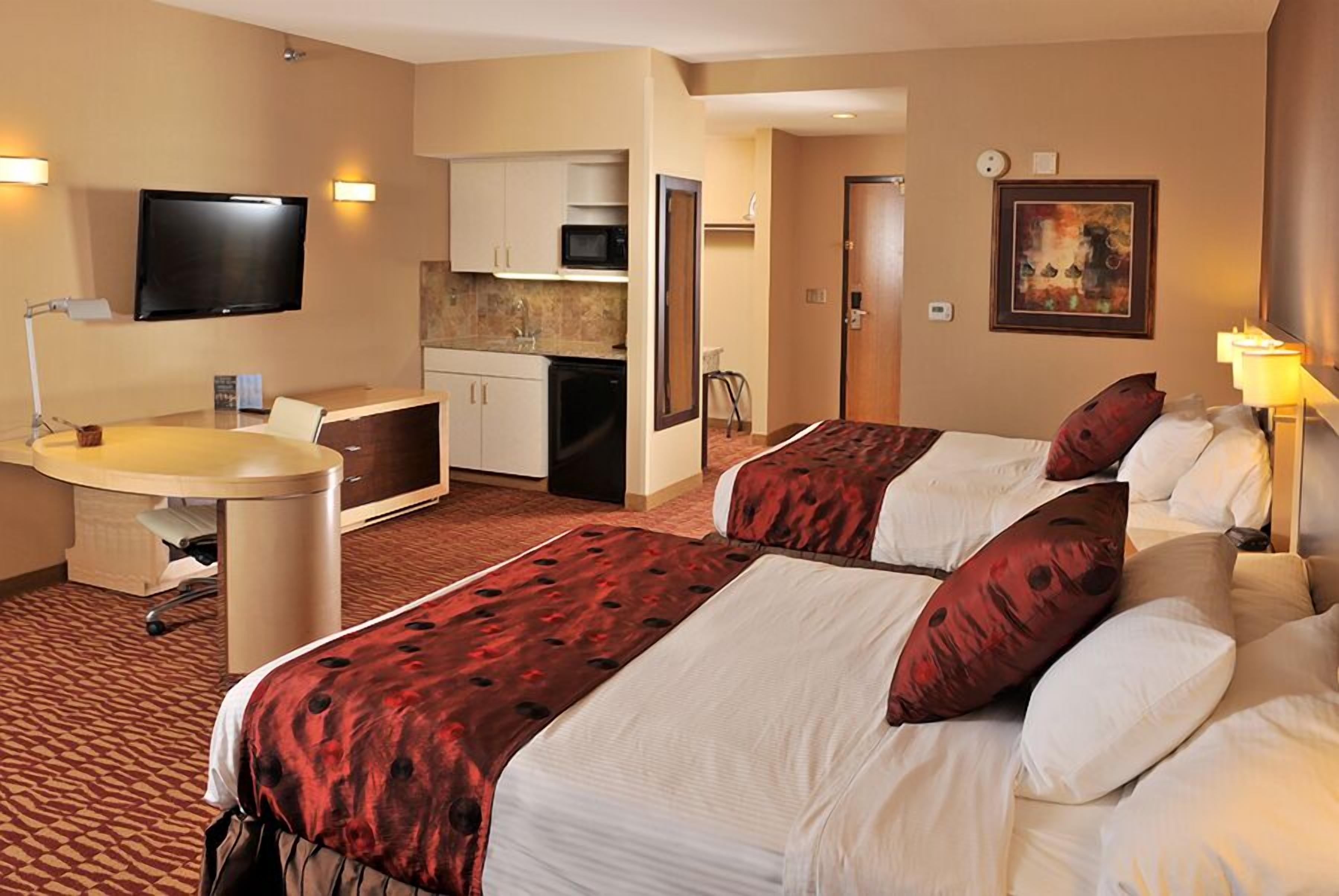 Una habitación de hotel con dos camas, un escritorio, un televisor, un microondas y una kitchenette.
