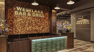 A reception area with a wooden hexagonal wall design and a sign reading 'WESTLAKE BAR & GRILL'.