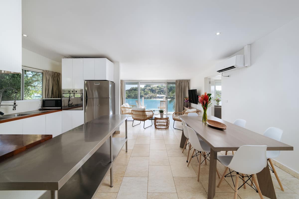 Cocina moderna con una isla grande, comedor con sillas y vista al mar.