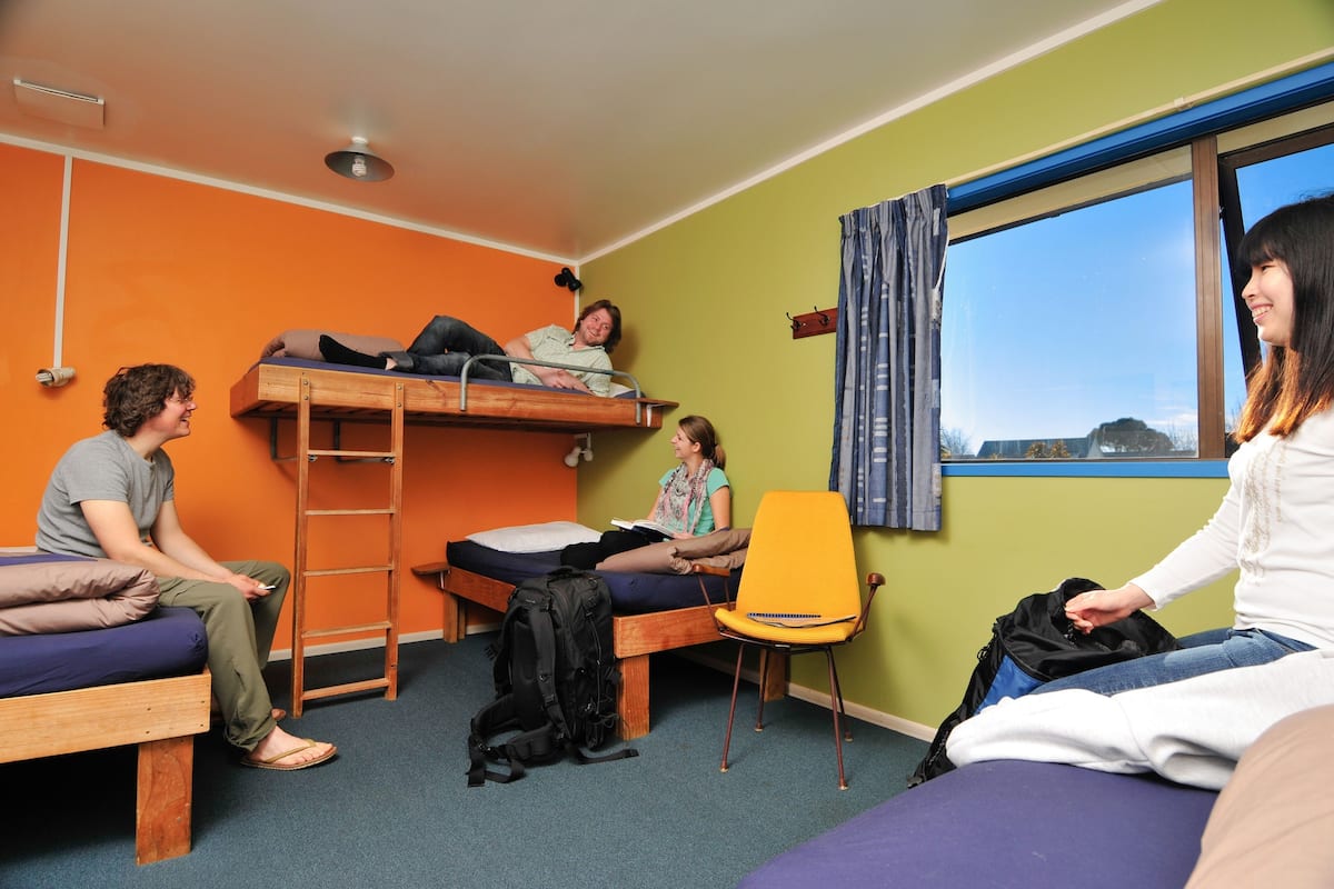 Une chambre de dortoir avec des lits superposés, une chaise et une fenêtre.