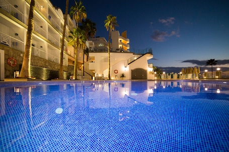 Una piscina al aire libre, sombrillas, sillones reclinables de piscina
