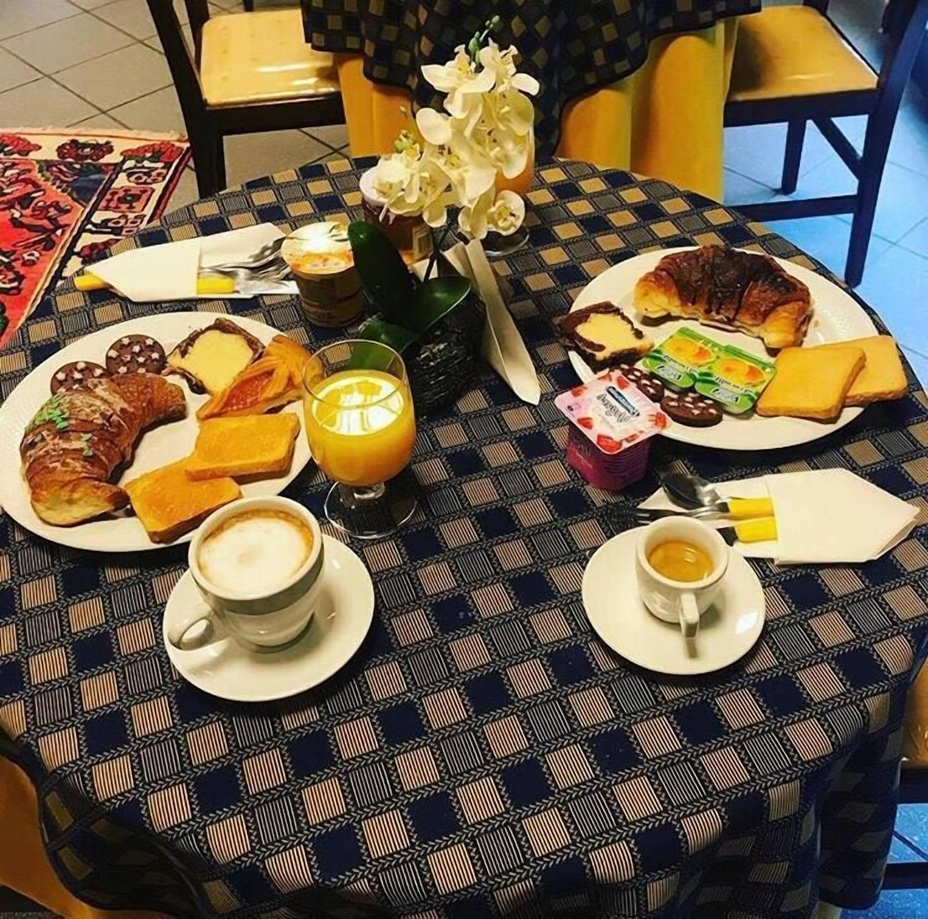 Une table de petit-déjeuner avec des croissants, du fromage, de la confiture et du café.