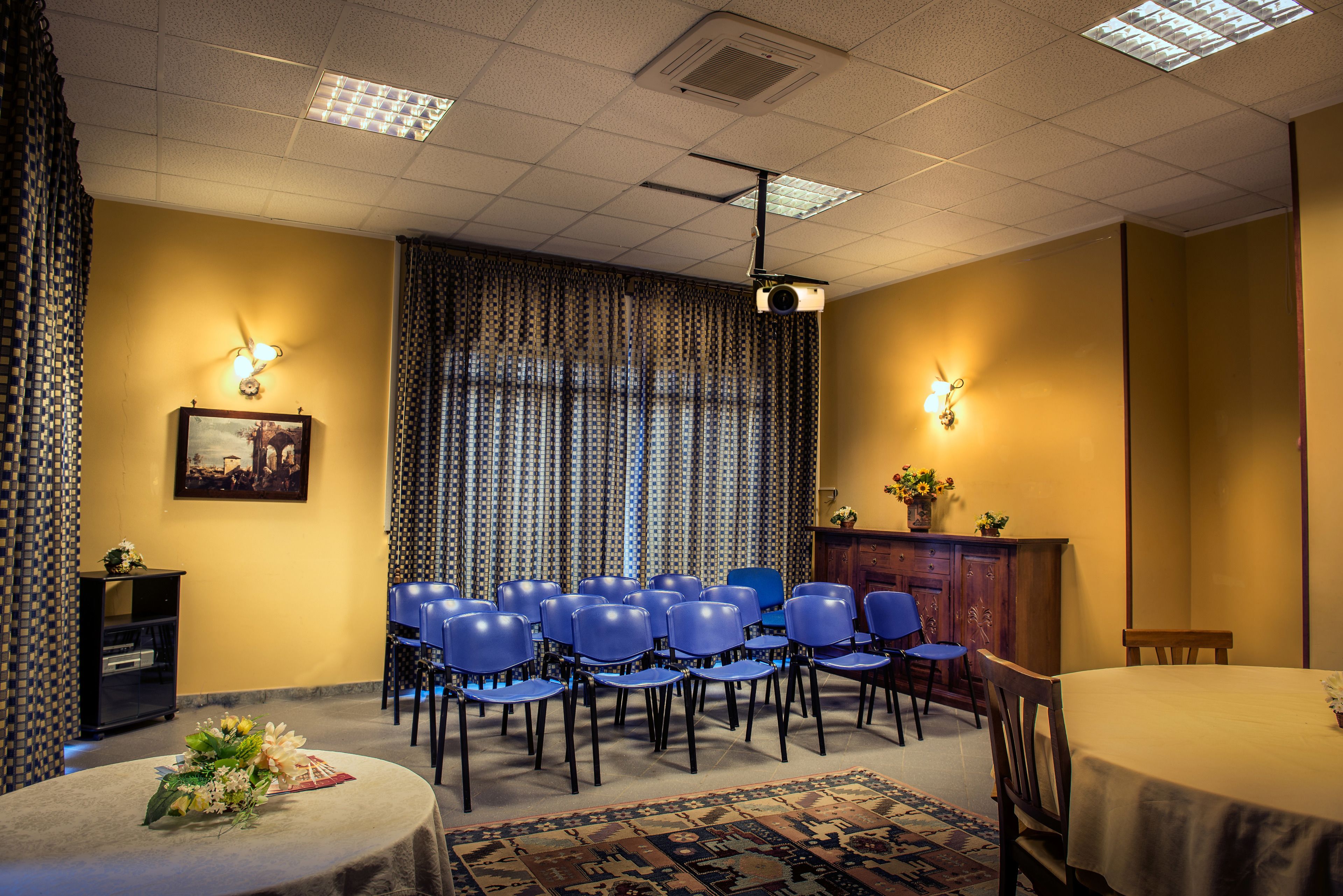A conference room with a projector, blue chairs, a table, and a patterned rug.