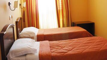 A hotel room with two beds, a TV, an air conditioner, and a telephone on a nightstand.