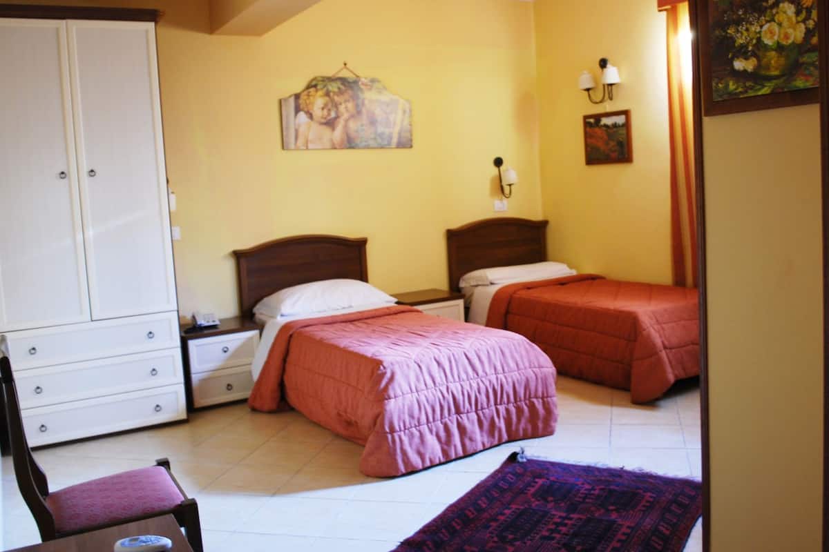 Une chambre avec deux lits, une armoire, une chaise et un tapis.