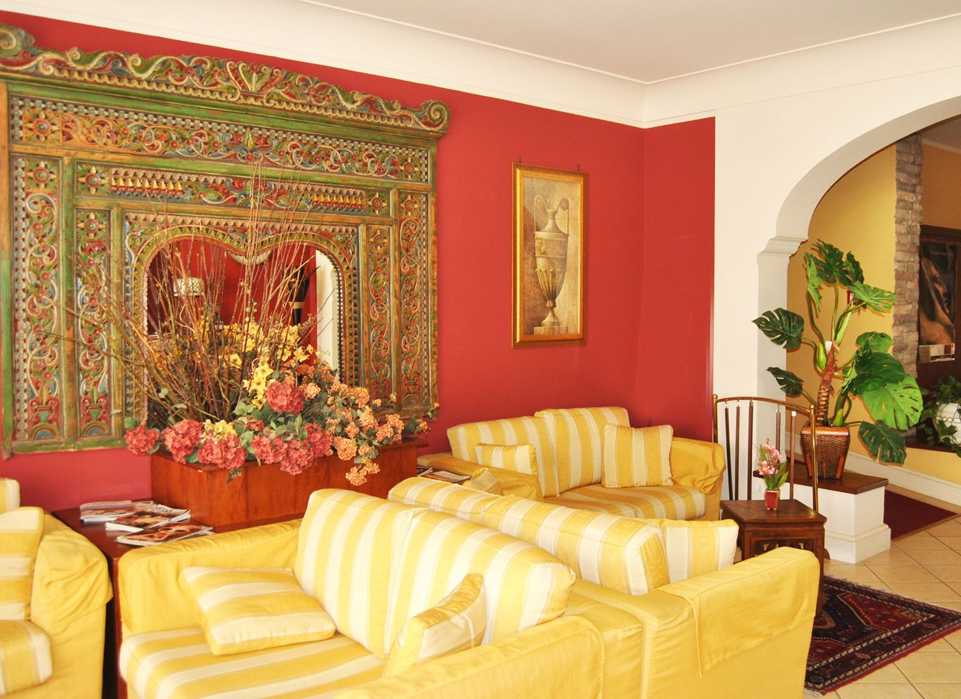 A living room with yellow-striped sofas, a large decorative mirror, and a potted plant.