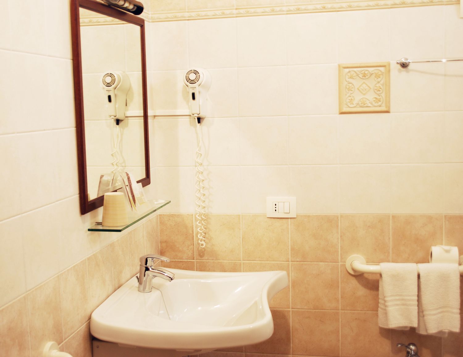 A bathroom with a sink, mirror, hairdryer, and towel rack.