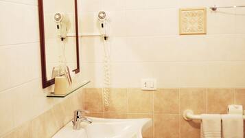 A bathroom with a sink, mirror, hairdryer, and towel rack.