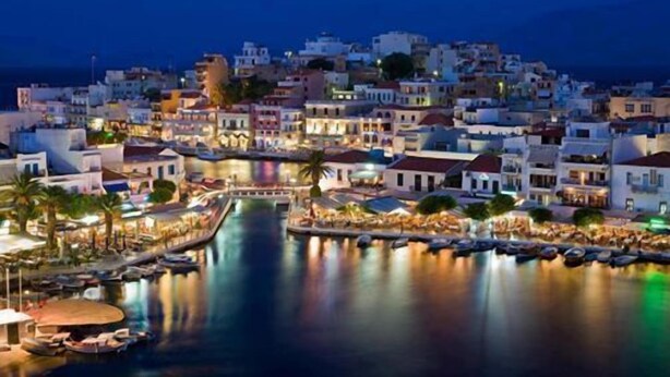 A coastal town at night with buildings, a marina, and a calm sea. - El Greco Apartments (Agios Nikolaos)