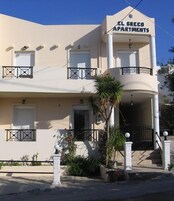 Un edificio de dos pisos con balcones y un letrero que dice "EL GRECO APARTMENTS".