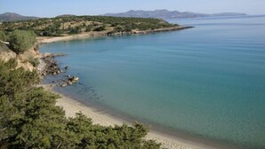 A coastal landscape with a clear view of the sea, a sandy beach, and a rocky shoreline. - El Greco Apartments (Agios Nikolaos)