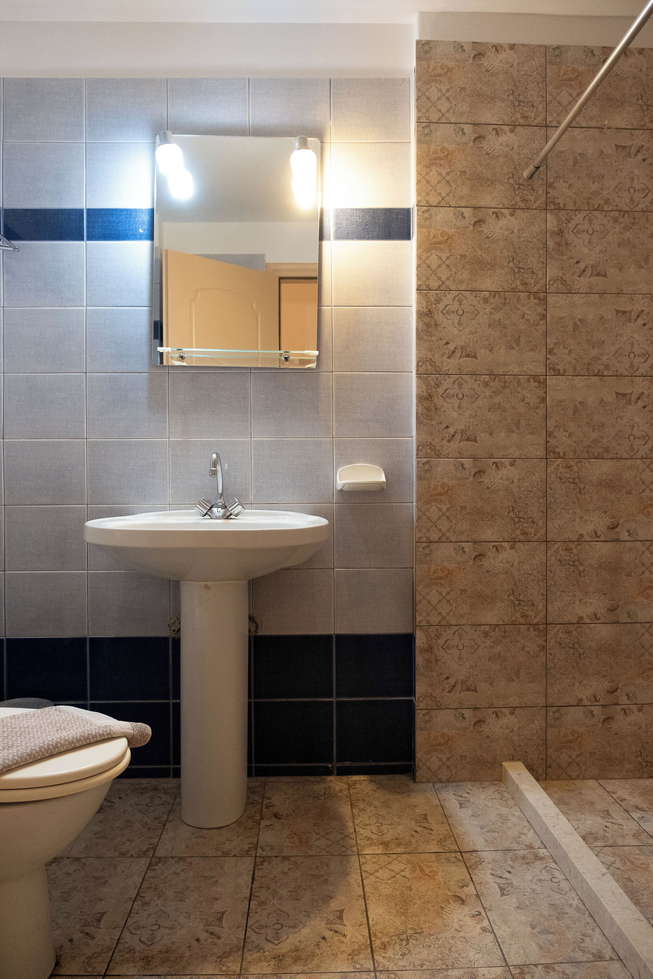 Egy fürdőszoba, amelyben mosdókagyló, tükör és WC található.