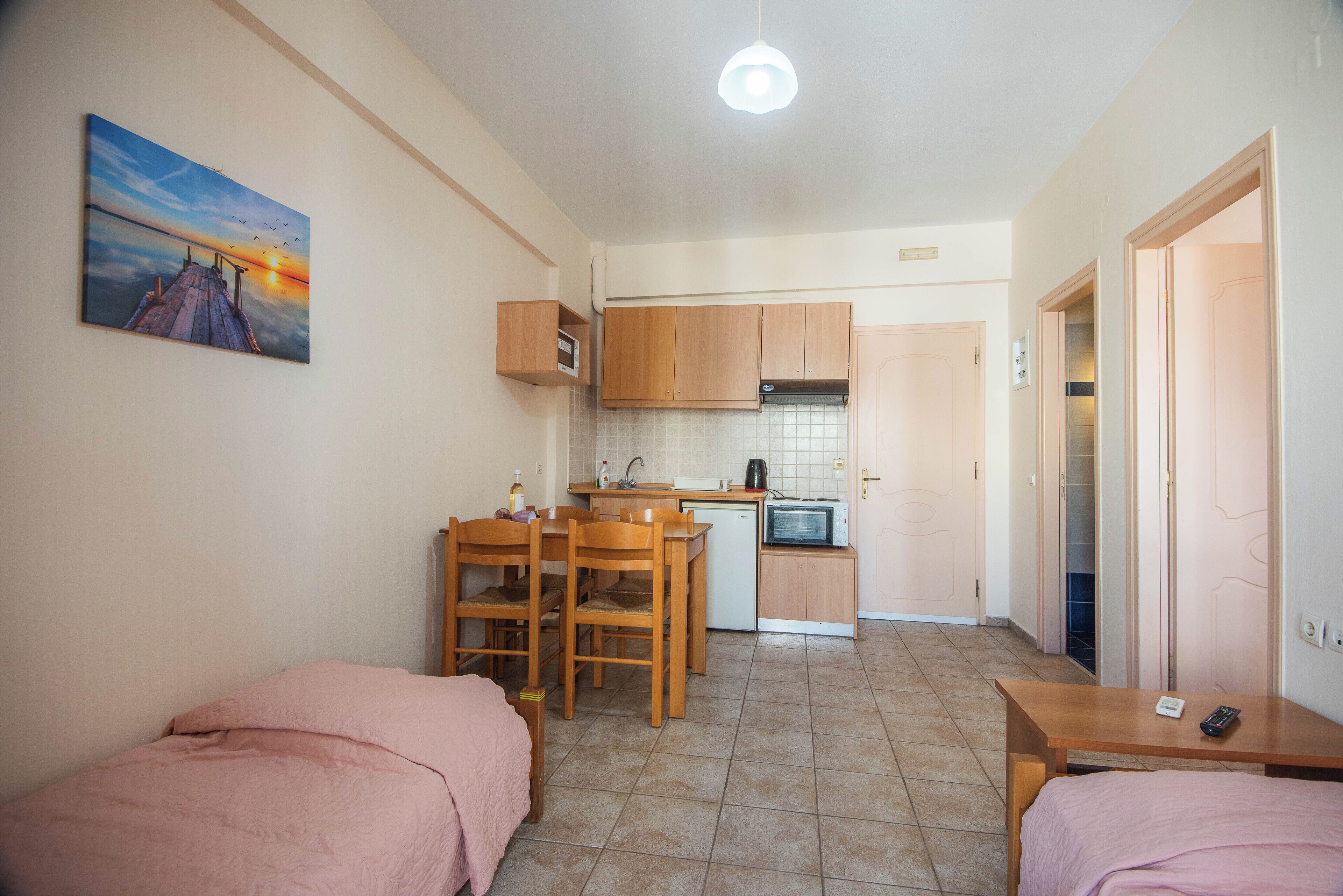 A compact room with a bed, a small dining table, and a kitchenette.