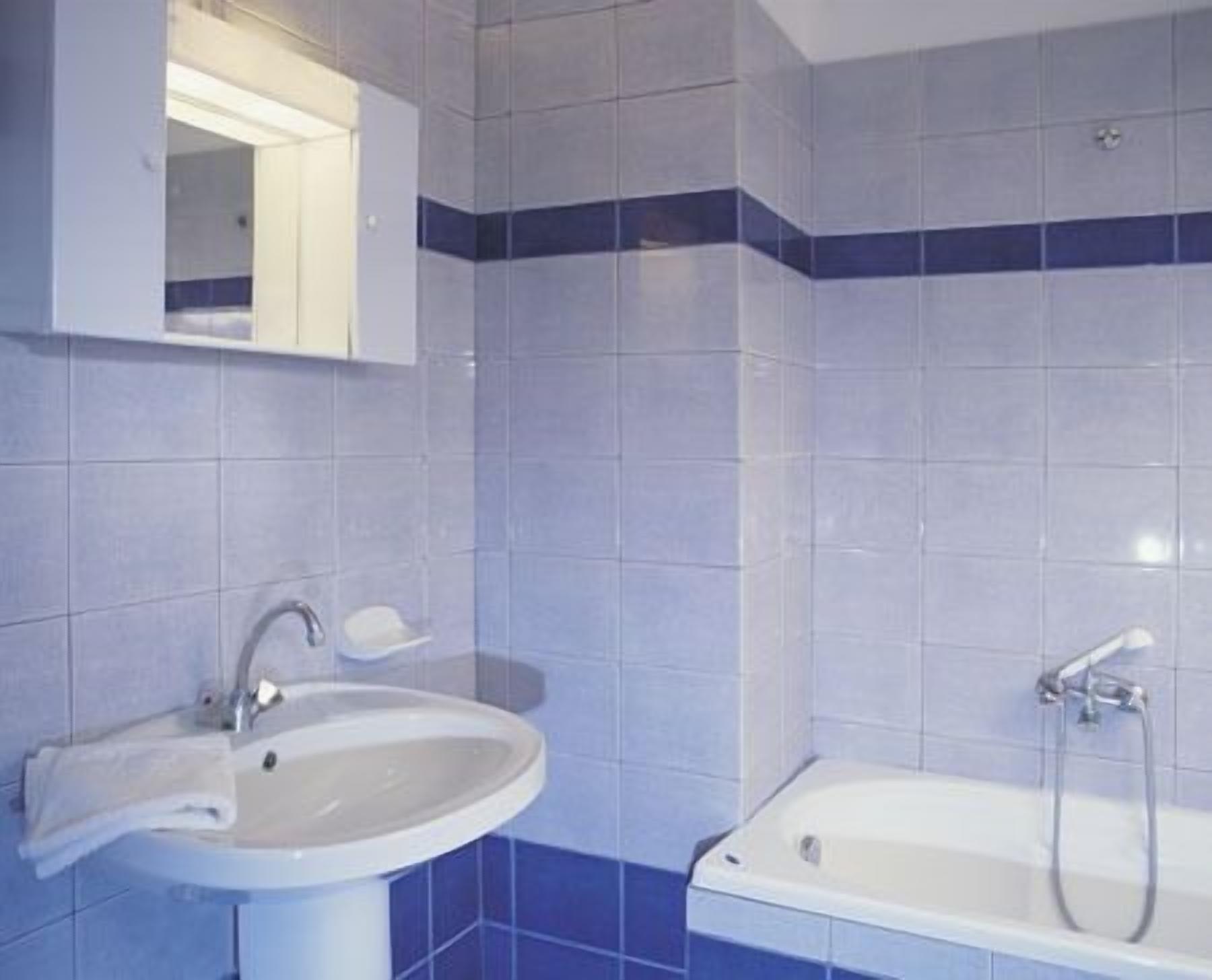 A bathroom with a sink, mirror, and bathtub.