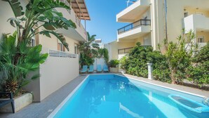 A swimming pool with lounge chairs and potted plants. - El Greco Apartments (Agios Nikolaos)