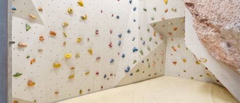 Una pared de escalar con diversos puntos de agarre y suelo acolchado.