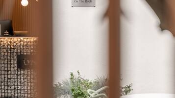 A reception area with a sign reading "On The Rock," a wooden desk, a hanging light, and white chairs.