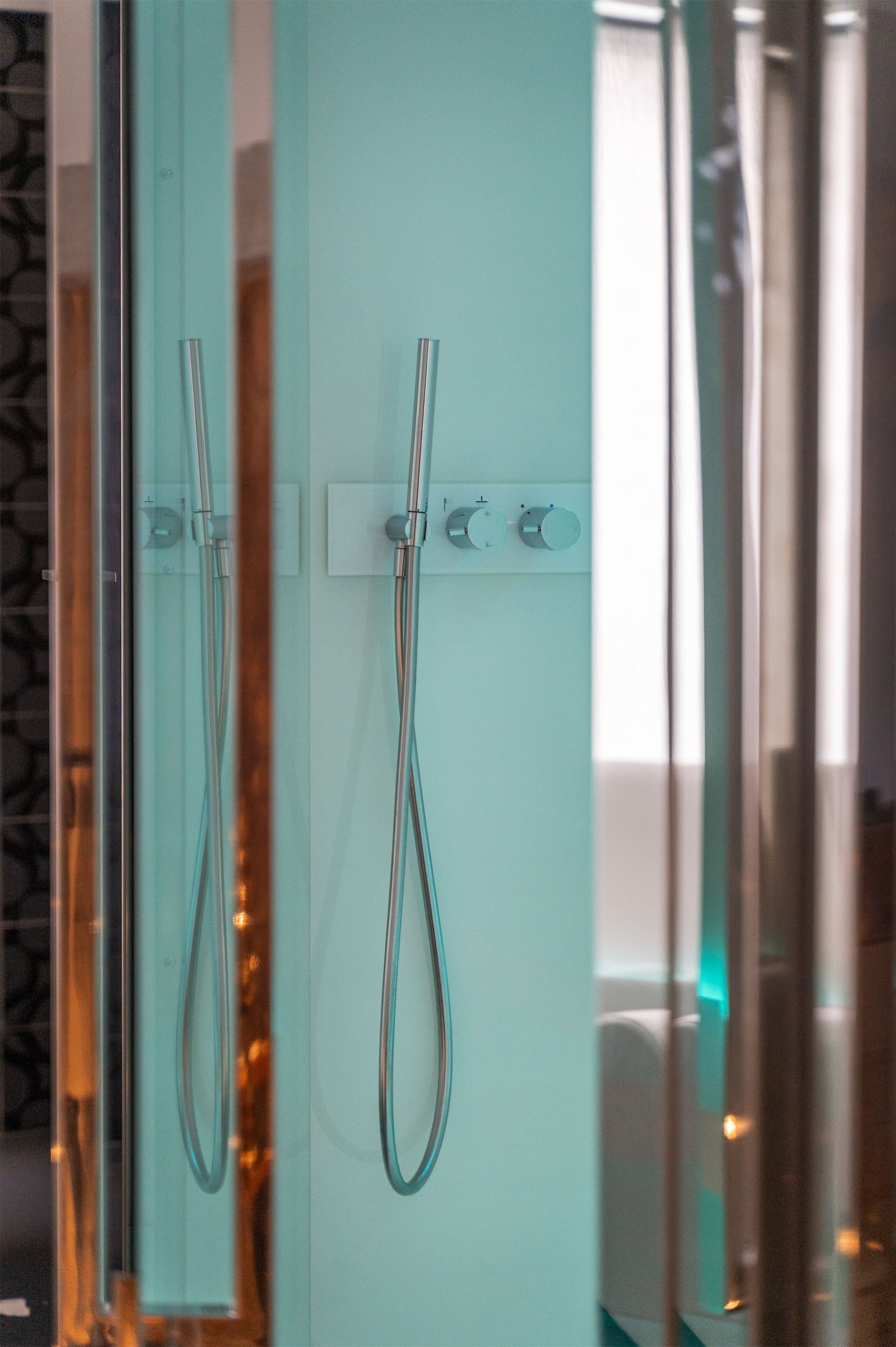 Un bagno moderno con cabina doccia in vetro, due soffioni e un pannello di controllo.