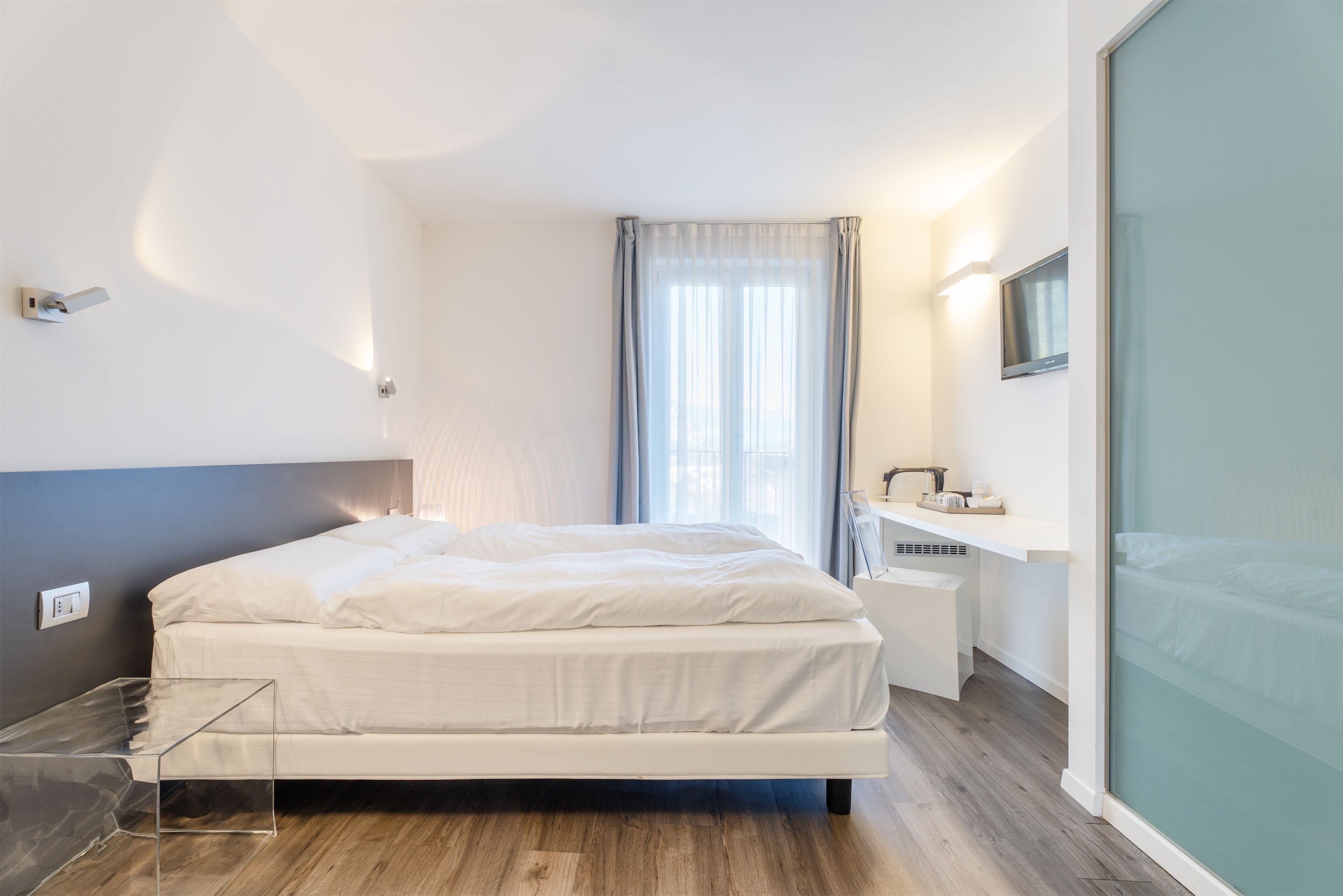 Une chambre moderne avec un lit, une table de chevet et une cloison en verre.