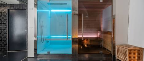 A modern bathroom with a glass shower enclosure, a wooden bench, and a small wooden chest.