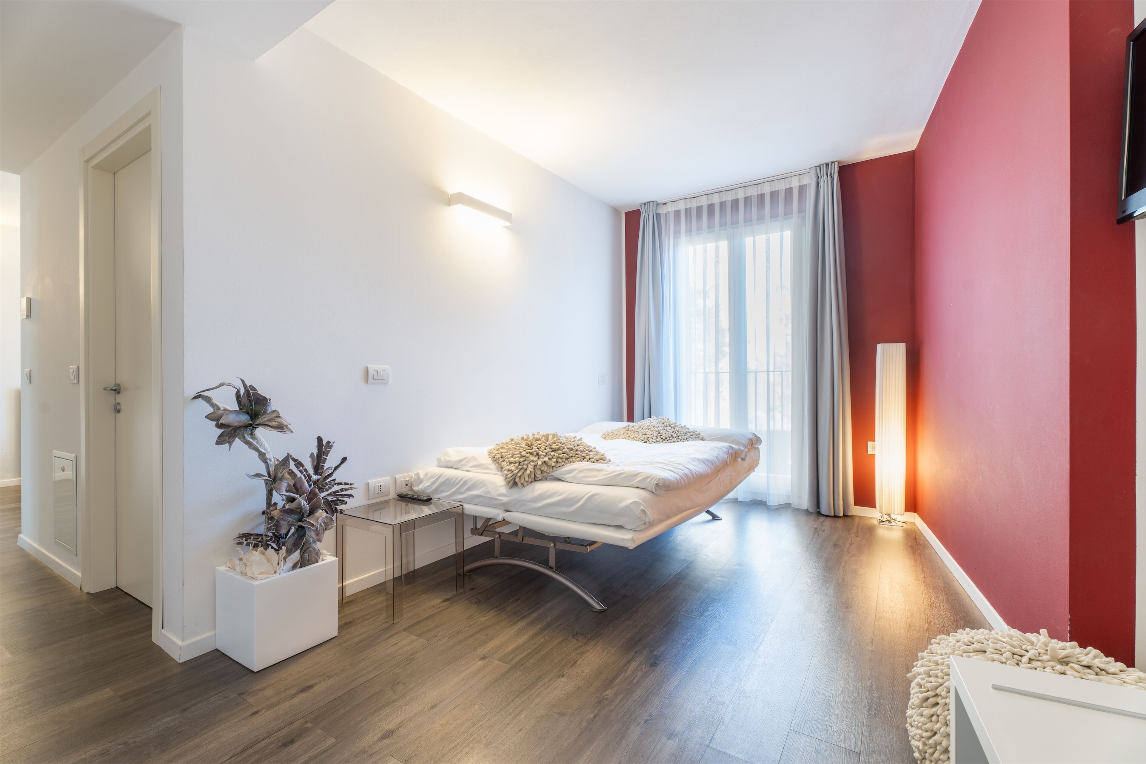A modern bedroom with a bed, bedside table, and a potted plant.