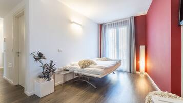 A modern bedroom with a bed, bedside table, and a potted plant.