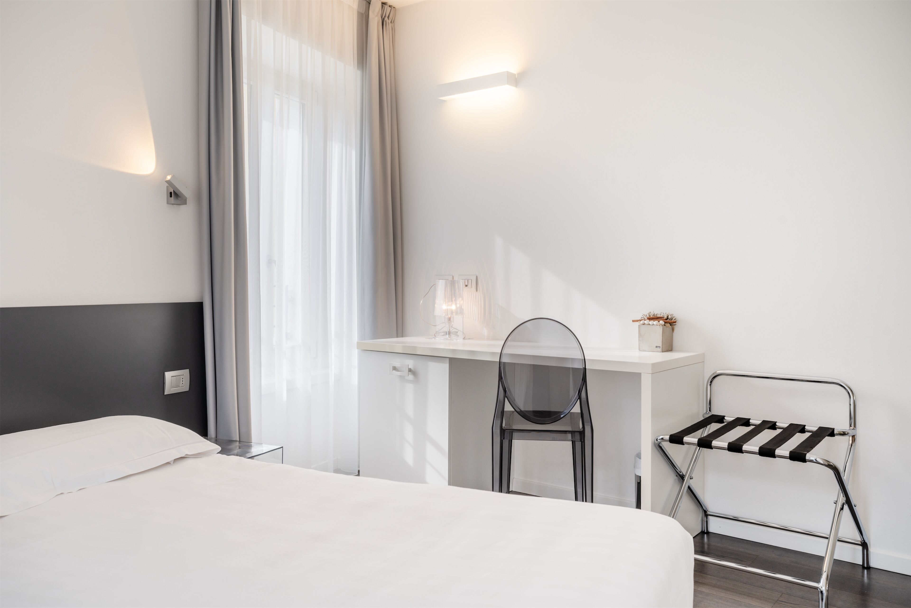 A modern hotel room with a bed, a desk, a chair, and a radiator.