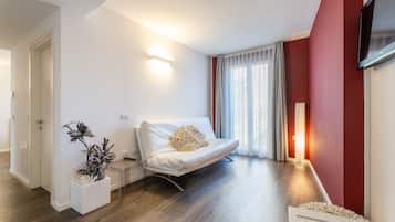 Ein modernes Wohnzimmer mit einer Couch, einem Beistelltisch, einem Blumentopf und einem flachbildfernseher an der Wand.