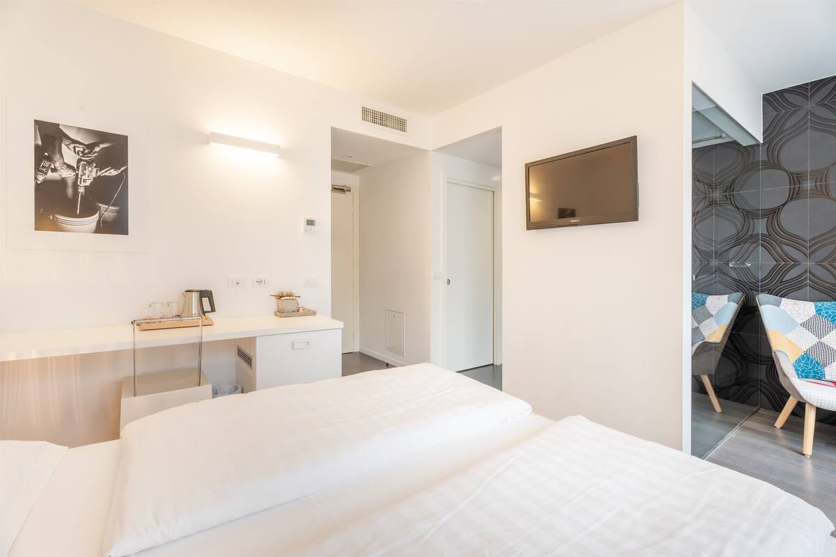 Ein modernes Hotelzimmer mit einem großen Bett, einem Schreibtisch mit Stuhl, einem Flachbildfernseher und einer Wand mit Muster.