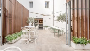A courtyard with outdoor seating, wooden partitions, and potted plants. - Garnì On The Rock (Arco)