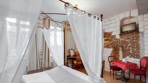 A room with a bed, a table with chairs, and a TV mounted on a brick wall. - Brit Hotel Les Comtes de Champagne Centre Historique (Troyes)